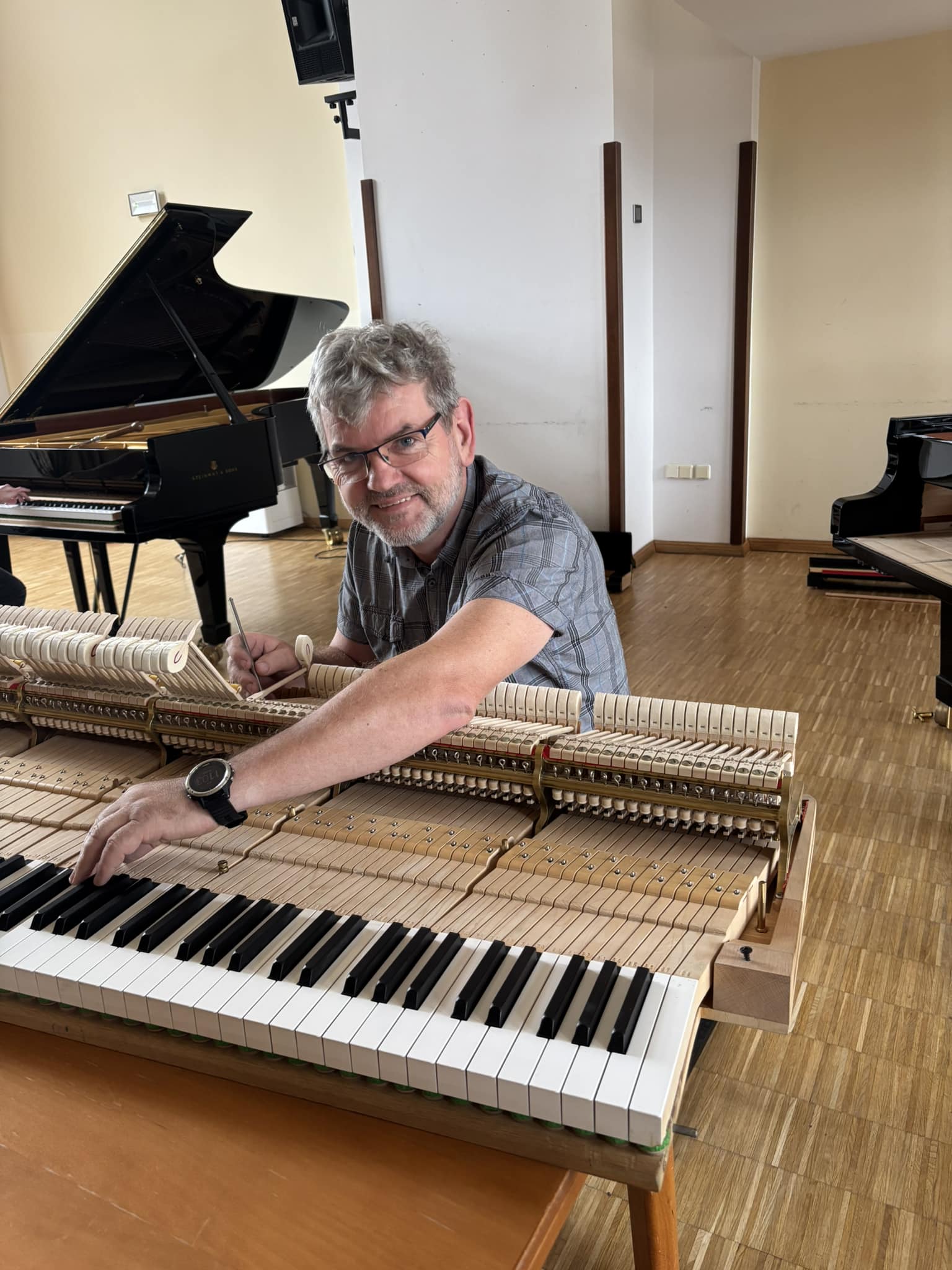 Zdjęcie przedstwiające Ryszarda Mariańskiego podczas strojenia fortepianu